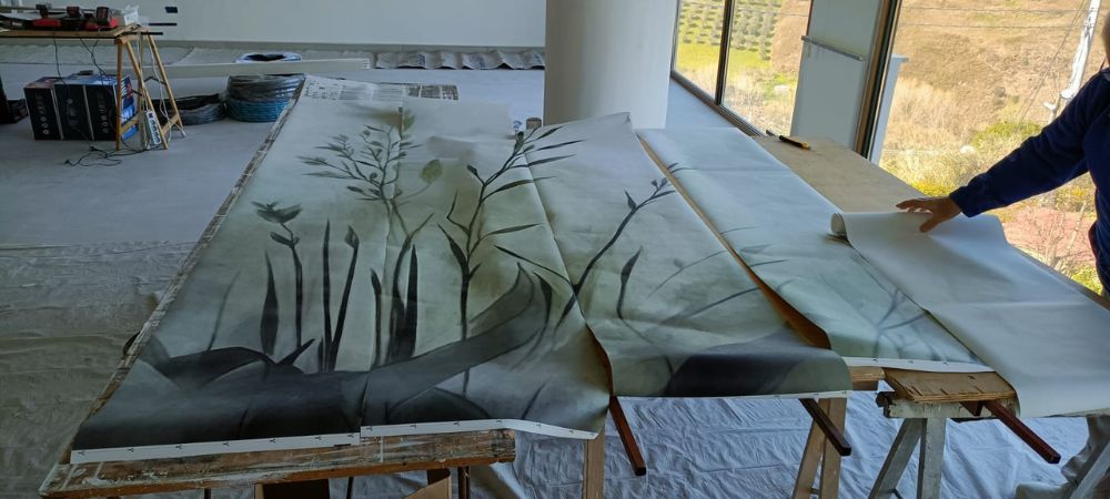 Rotolo di carta da parati con motivo botanico dipinto a mano, in preparazione per il rivestimento dei pilastri di una location matrimoni